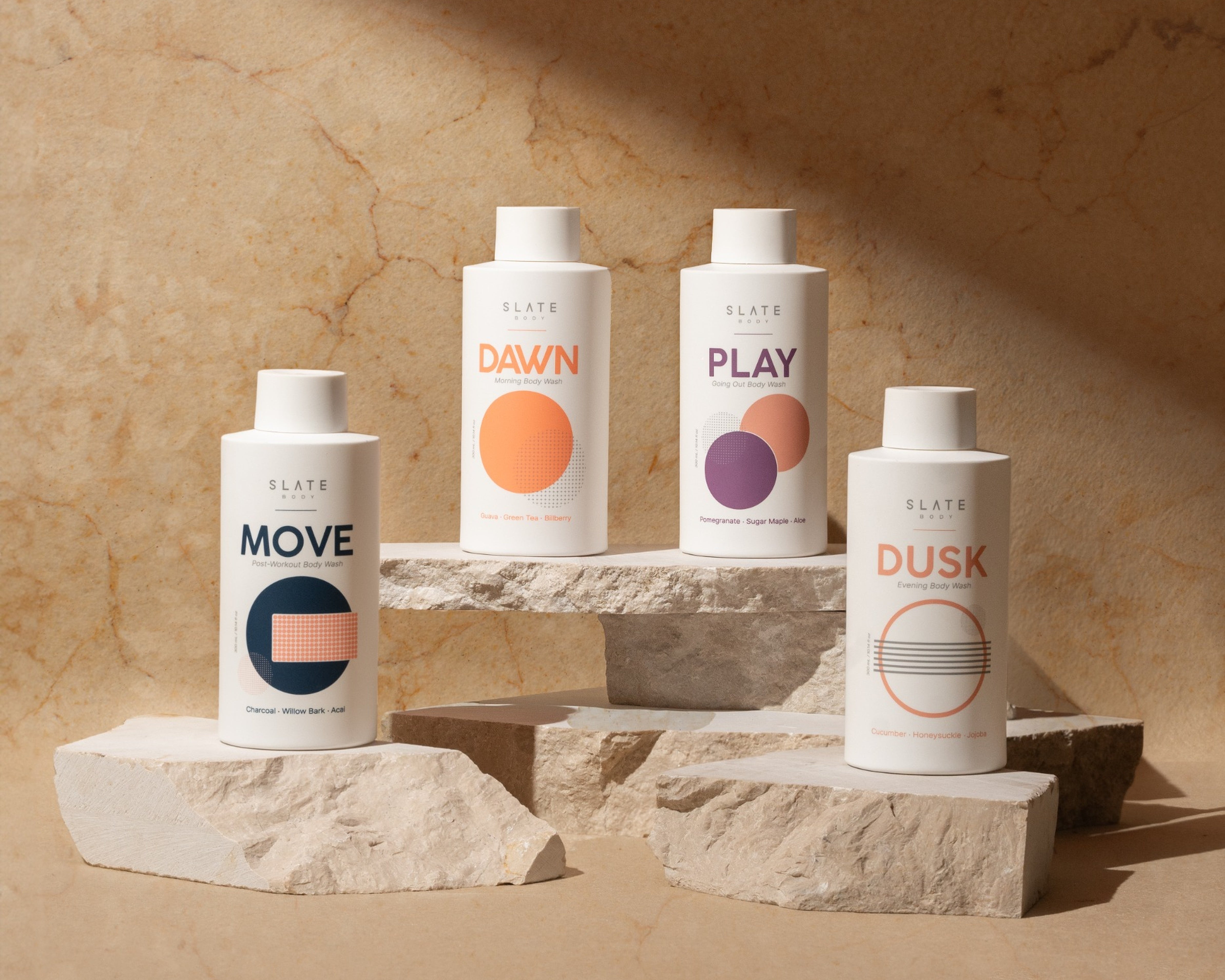 Four skincare bottles labeled 'Move', 'Dawn', 'Play', and 'Dusk' on a stone surface with a beige background.
