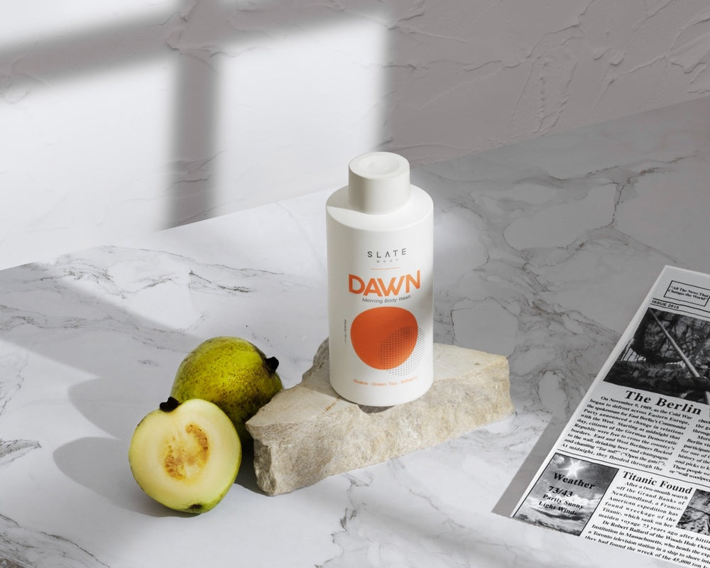 A refined flatlay of DAWN Morning Body Wash featuring fresh guava, green tea, and a moment of morning calm. This shot evokes both sophistication and routine with a nod to natural ingredients
