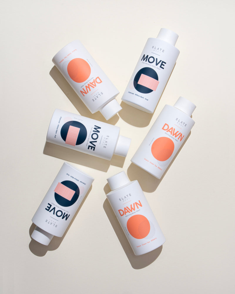 Multiple bottles of a shower gel product labeled 'MOVE' and 'DAWN' on a light background