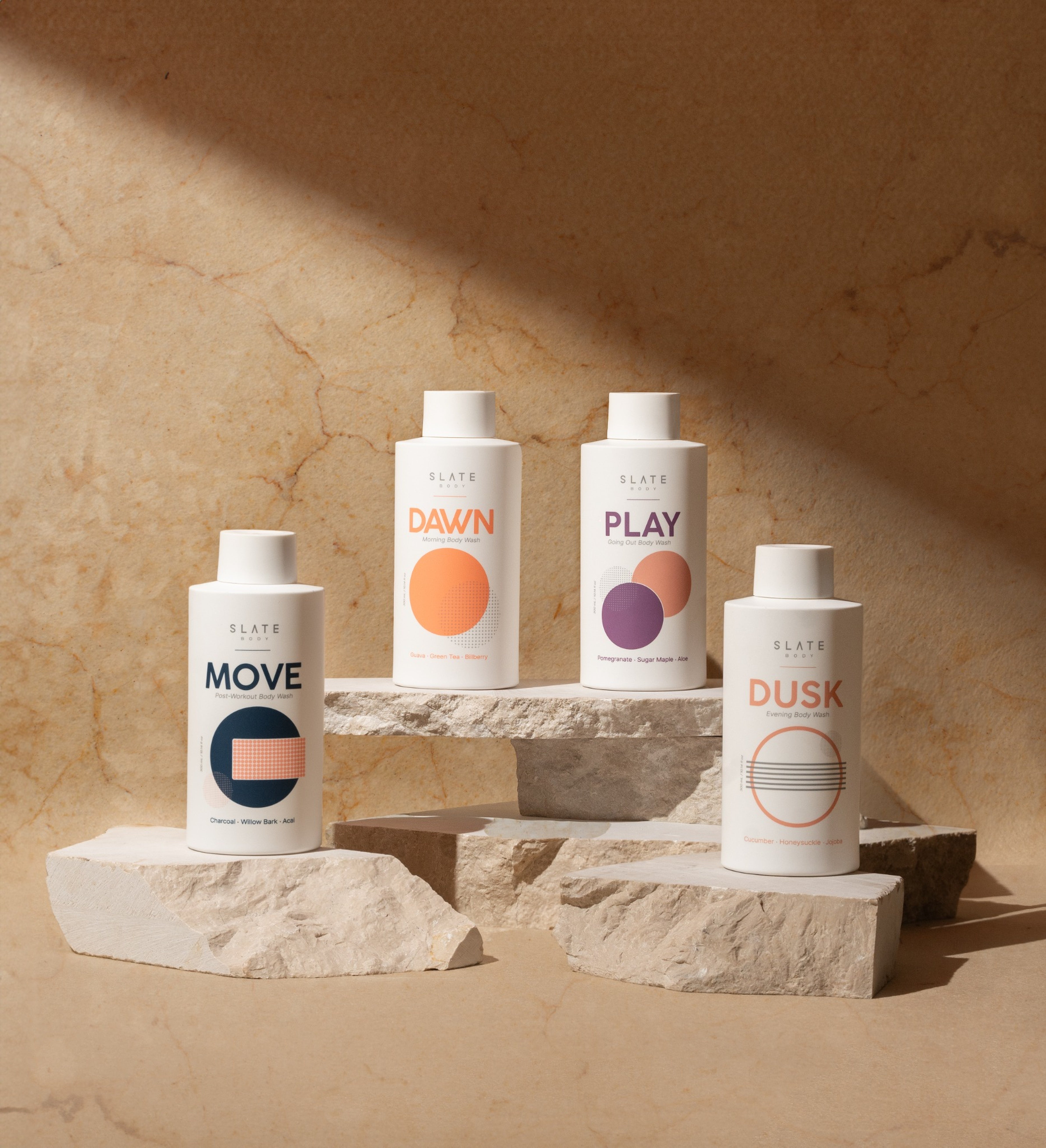 Four skincare bottles labeled 'Move', 'Dawn', 'Play', and 'Dusk' on a stone surface with a beige background.